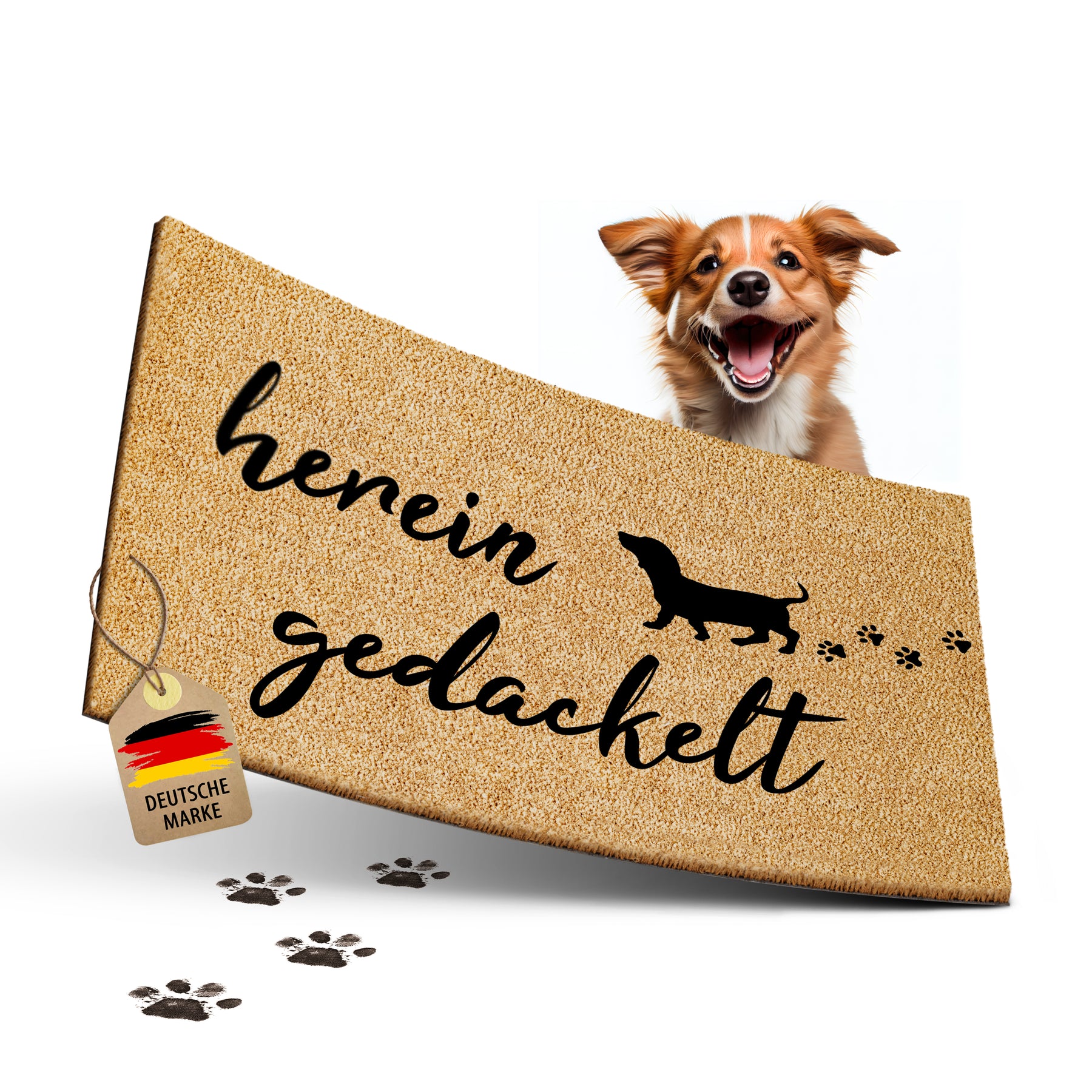 Freigestellte ElbFuchs Kokos-Fußmatte mit der handschriftlichen Aufschrift 'herein gedackelt', einer Dackel-Silhouette und Pfotenabdrücken, über deren Rand ein freundlicher Hund neugierig hervorschaut.
