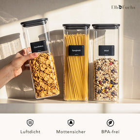 Hand hält ein hohes ElbFuchs BLACK KONTOR Vorratsglas mit Pasta vor weiteren Gläsern mit Spaghetti und Reis – luftdicht, mottensicher und BPA-frei.