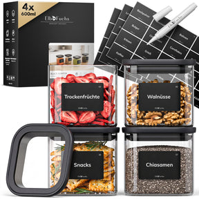 Vier ElbFuchs BLACK KONTOR Vorratsgläser à 600 ml mit schwarzem Deckel, gefüllt mit Trockenfrüchten, Walnüssen, Snacks und Chiasamen, inklusive Etiketten und Kreidestift.