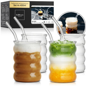 Vier ElbFuchs BYSKE Gläser im Set 4x 400ml mit ihrer charakteristischen wellenförmigen Form, zwei davon gefüllt mit Iced Coffee und Iced Matcha Latte samt Glasstrohhalmen und Verpackung im Hintergrund.