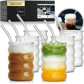 Sechs ElbFuchs BYSKE Trinkgläser mit geschwungener, geriffelter Form im Set 6x 400ml, teils gefüllt mit Iced Coffee und Iced Matcha Latte samt Glasstrohhalmen, daneben die Verpackung und eine Nahaufnahme der Eiskaffee-Gläser.