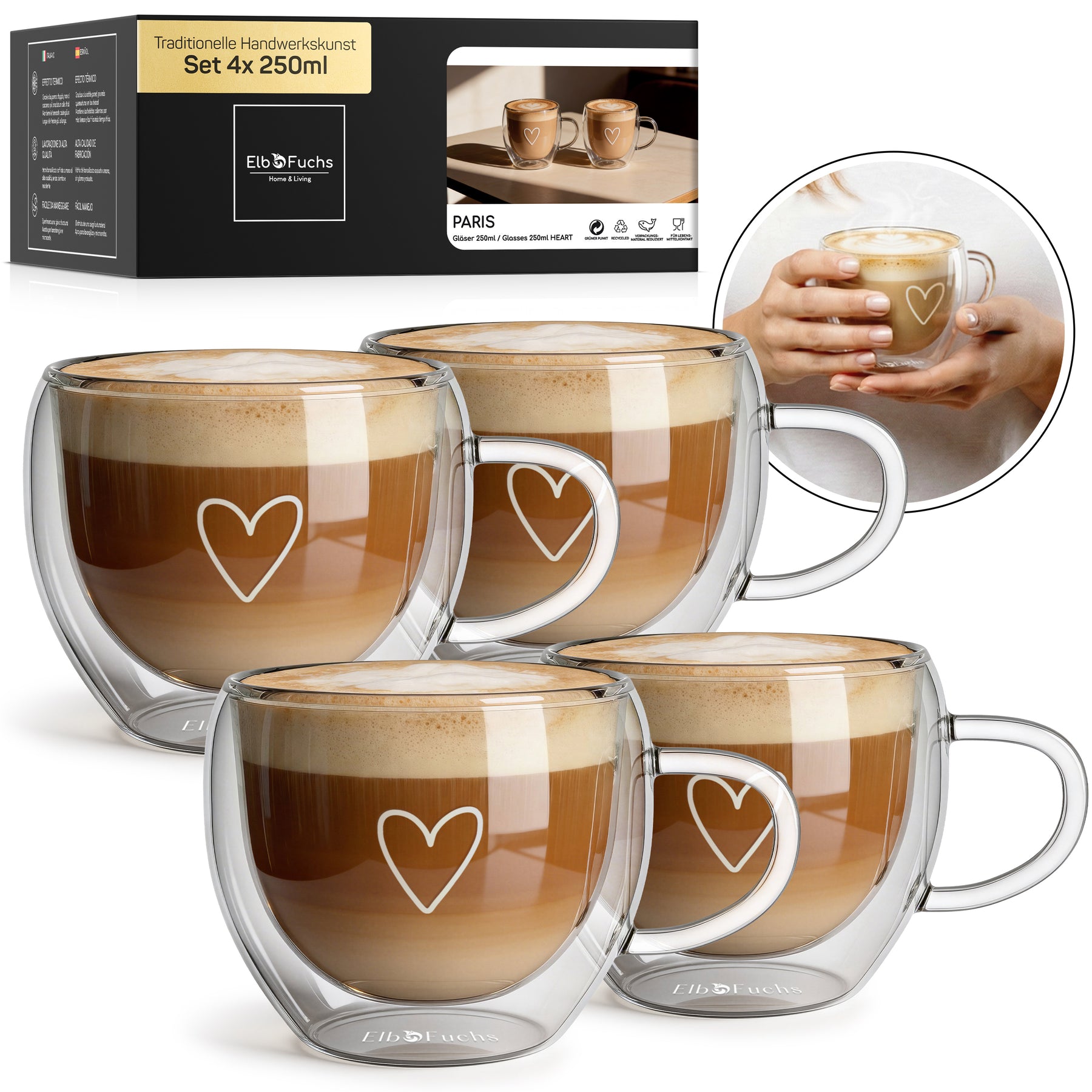 Vier ElbFuchs PARIS Cappuccino-Tassen mit doppelwandigem Glas, Henkel und Herzgravur, gefüllt mit cremigem Milchkaffee im Set 4x 250ml, mit Verpackung und einer Nahaufnahme haltender Hände im Hintergrund.