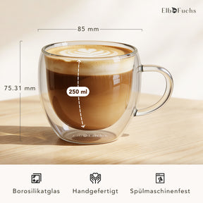 Ein doppelwandiges ElbFuchs VIENNA Kaffeeglas mit Henkel, gefüllt mit Cappuccino und feiner Latte-Art, mit eingeblendeten Maßen von 85 mm Durchmesser und 250 ml Fassungsvermögen aus handgefertigtem, spülmaschinenfestem Borosilikatglas.