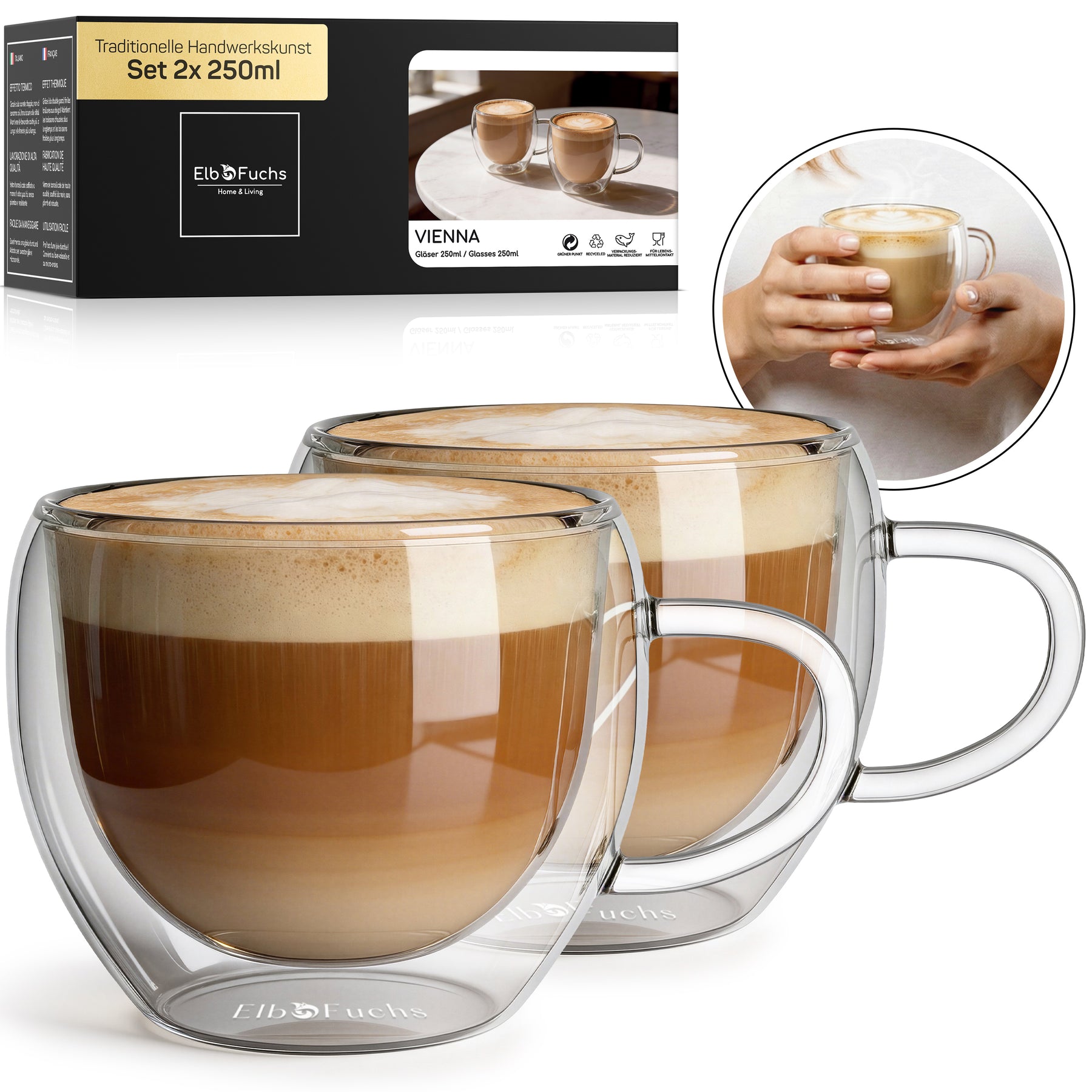 Zwei doppelwandige VIENNA Kaffeegläser mit Henkel, gefüllt mit cremigem Milchkaffee, stehen nebeneinander vor der ElbFuchs Verpackung im Set 2x250ml, ergänzt durch ein rundes Foto zweier Hände, die ein Glas umschließen.