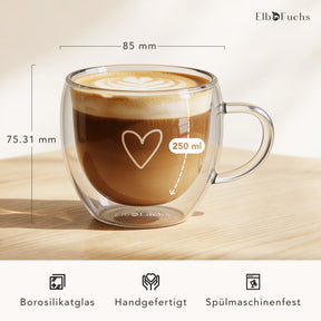 Ein doppelwandiges ElbFuchs PARIS Kaffeeglas mit Henkel, gefüllt mit Cappuccino und Latte-Art, mit eingeblendeten Maßen von 85 mm Durchmesser und 250 ml Fassungsvermögen aus handgefertigtem, spülmaschinenfestem Borosilikatglas.