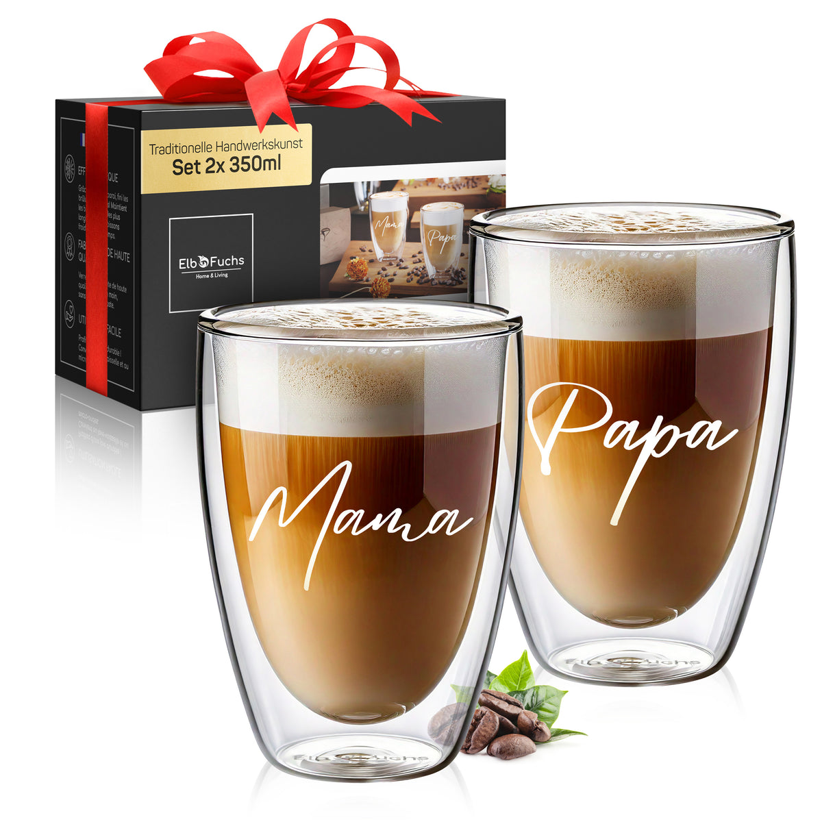 Vier doppelwandige ElbFuchs Gläser mit Latte Macchiato und feinem Milchschaum stehen auf einem Holztisch zwischen Kaffeebohnen, Keksen und einem Stück Kuchen, das mittlere Glas ziert die goldene Gravur 'Moin' neben einem Glas mit Anker-Motiv vor dunklem, stimmungsvollem Hintergrund.