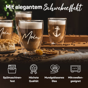 Mehrere ElbFuchs Latte-macchiato-Gläser mit Schwebeeffekt, Ankergravur und dem Schriftzug 'Moin', dekoriert auf einem Holzbrett mit Kaffeebohnen, Keksen und Kuchen, umgeben von Symbolen für Spülmaschinenfestigkeit und mundgeblasenes Glas.