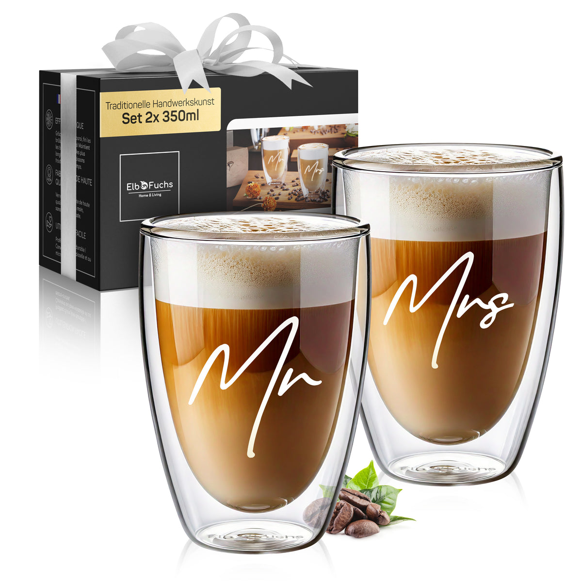 Zwei ElbFuchs Latte-macchiato-Gläser mit den Gravuren 'Mr' und 'Mrs' vor der dazugehörigen schwarzen Geschenkbox mit Schleife und Kakaobohnen als Dekoration – ein Hochzeitsgeschenk-Set mit 2x 350 ml.