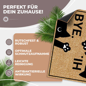 Illustration der ElbFuchs Kokos-Fußmatte mit Katzenmotiv 'HI.' und 'BYE.', die leicht angehoben die rutschfeste schwarze Unterseite zeigt, mit Hinweisen zu Robustheit und einfacher Reinigung.