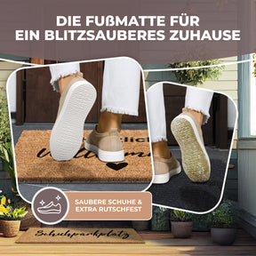 Nahaufnahme zweier Schuhsohlen beim Abstreifen auf der ElbFuchs Kokos-Fußmatte mit dem Schriftzug 'Herzlich Willkommen', mit dem Hinweis 'Saubere Schuhe & extra rutschfest' vor einem unscharfen Hauseingang.
