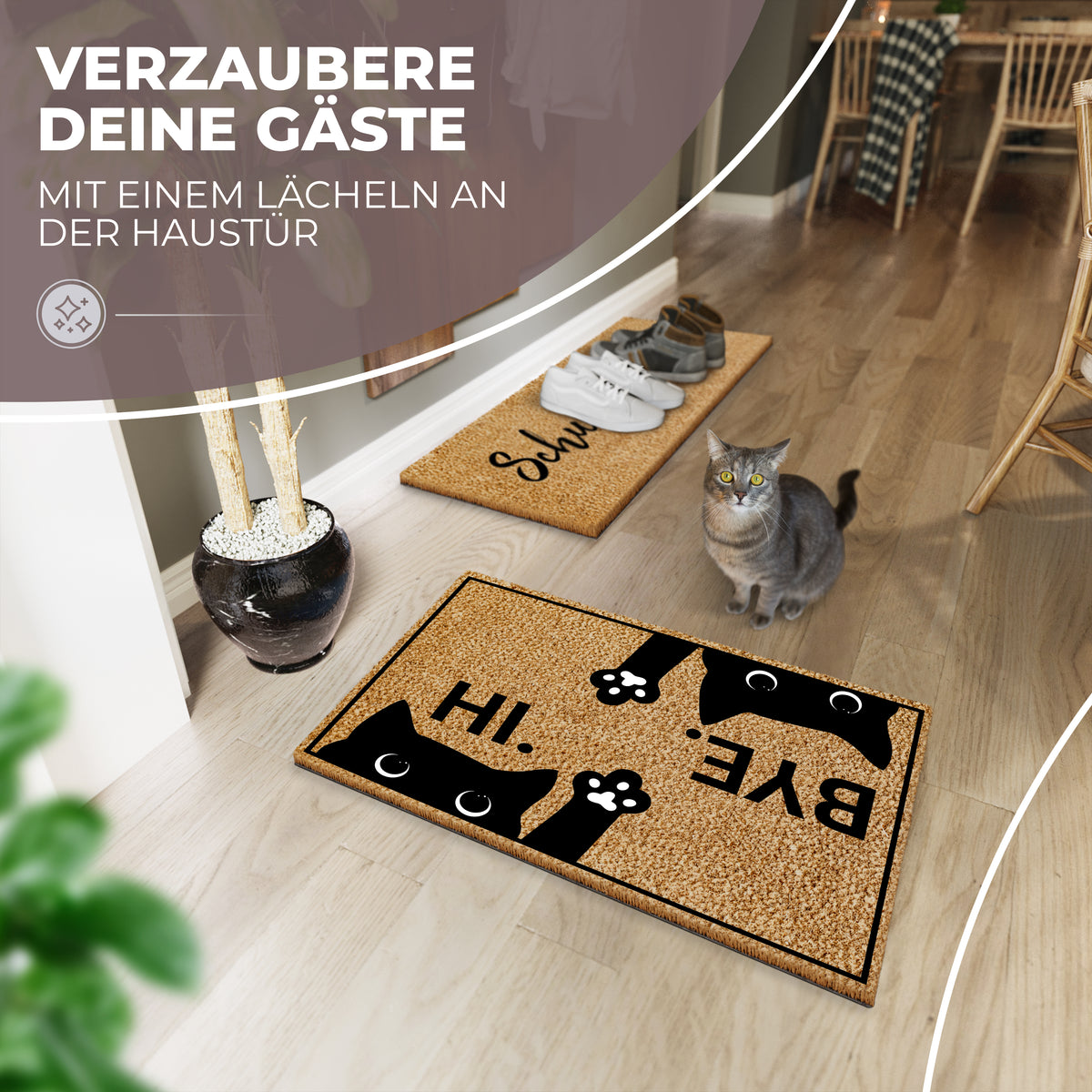 Die ElbFuchs Kokos-Fußmatte mit schwarzem Katzenmotiv und der Aufschrift 'HI.' und 'BYE.' liegt vor der Haustür in einem hellen Flur, während eine echte Katze neben einer zweiten Schuhmatte steht.