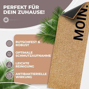 Hochgeklappte Ecke einer ElbFuchs Kokos-Fußmatte mit senkrecht angeordnetem Schriftzug 'MOIN.', die die schwarze rutschfeste Unterseite freigibt, umrahmt von Palmblättern und Icons zu Rutschfestigkeit, Schmutzaufnahme und antibakterieller Wirkung.