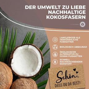 Eine halbierte Kokosnuss und Palmblätter veranschaulichen die nachhaltigen Fasern der ElbFuchs Fußmatte „Schön, dass du da bist!“, ergänzt durch Hinweise zu biologischer Abbaubarkeit und langer Haltbarkeit.