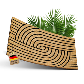 ElbFuchs Kokos-Fußmatte 'Harmony Stripes' 60x40 cm mit gebogenem Streifen- und Spiralmuster, leicht gebogen freigestellt vor weißem Hintergrund, mit Anhänger 'Deutsche Marke' und Palmblättern.