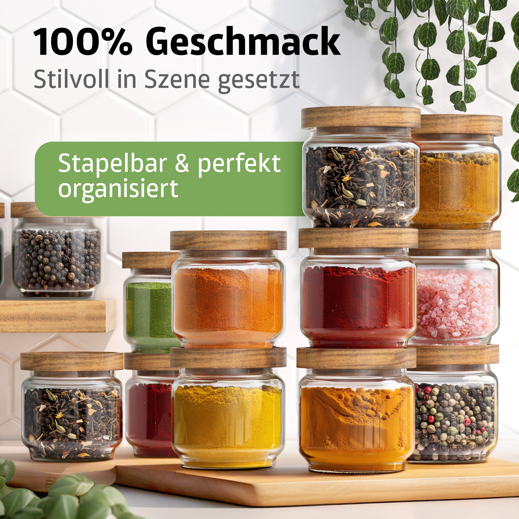 Zahlreiche ElbFuchs Gewürzgläser mit Holzdeckel sind stapelbar auf einem Holzbrett arrangiert und mit getrockneten Kräutern, Kurkuma, Paprikapulver, rosa Salz und bunten Pfefferkörnern gefüllt, umgeben von herabhängenden grünen Blättern in einer hellen Küche.