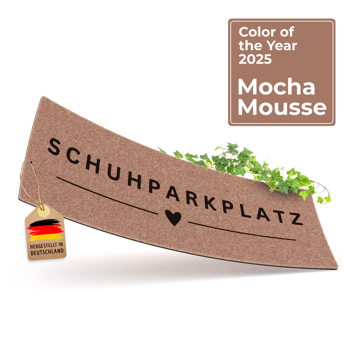 Eine mokkabraune ElbFuchs Schuhparkplatz Fußmatte mit dem Schriftzug 'Schuhparkplatz' und einem Herz-Symbol, dekoriert mit grünem Efeu und einem Hinweis auf die Trendfarbe 'Mocha Mousse' des Jahres 2025.