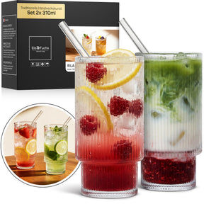 Zwei ElbFuchs RILA Gläser im Set 2x 310ml, gefüllt mit einem Himbeer-Zitronen-Drink und einem grünen Matcha-Minz-Drink samt Eiswürfeln und Glasstrohhalmen, mit Verpackung und einer Nahaufnahme im Hintergrund.
