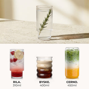 Ein geriffeltes ElbFuchs Glas mit Rosmarinzweig auf einer hellen Steinplatte, darunter die drei Serien RILA mit 310ml, BYSKE mit 400ml und CERNO mit 450ml, jeweils mit einem passenden bunten Getränk dargestellt.