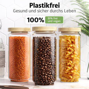 Drei ElbFuchs Vorratsgläser WOOD KONTOR mit Holzdeckeln stehen nebeneinander auf einer Marmorplatte, gefüllt mit roten Linsen, Kaffeebohnen und gelben Fusilli, vor weißen Hexagonfliesen mit grüner Pflanze.