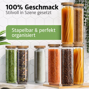 Eine Reihe schlanker ElbFuchs Vorratsgläser mit Bambusdeckel steht aufgereiht vor einer weißen Fliesenwand, gefüllt mit grünen Erbsen, Teeblättern, Salz, roten Linsen, Kaffeebohnen und Spaghetti in unterschiedlichen Höhen.