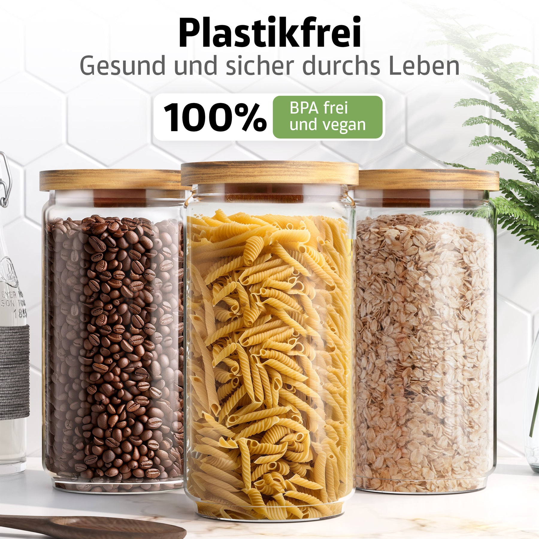 Drei ElbFuchs Vorratsgläser mit Bambusdeckel stehen nebeneinander auf einer Küchenarbeitsplatte, gefüllt mit Kaffeebohnen, Nudeln und Haferflocken; ein Siegel bestätigt das 100 % plastikfreie, BPA-freie und vegane Material.