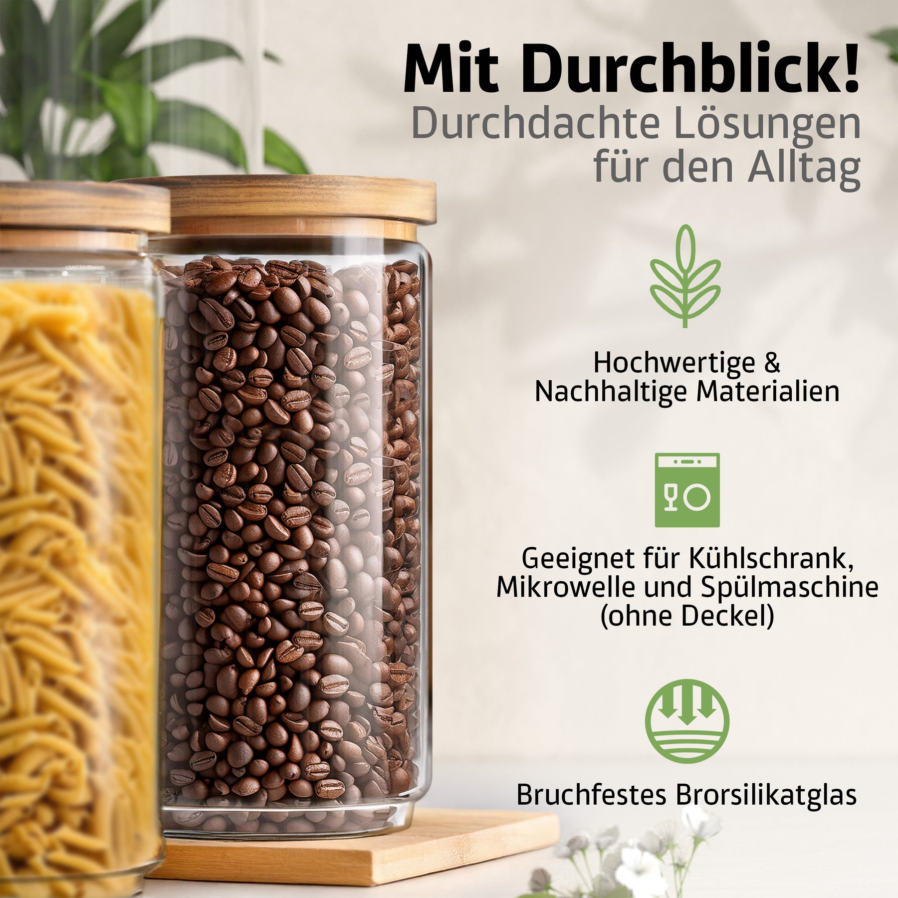 Zwei große ElbFuchs Vorratsgläser mit Bambusdeckel und bruchfestem Borosilikatglas stehen auf einem Holzbrett, das vordere randvoll mit Kaffeebohnen, das andere mit Spaghetti gefüllt, umgeben von zarten weißen Blüten.
