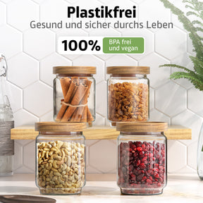Vier ElbFuchs Vorratsgläser WOOD KONTOR mit Holzdeckeln stehen auf einem Holzbrett, gefüllt mit Zimtstangen, goldenen Rosinen, Cashewkernen und getrockneten Cranberries, vor weißen Hexagonfliesen mit grüner Pflanze.