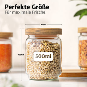 Ein ElbFuchs Vorratsglas WOOD KONTOR mit Holzdeckel und Perlgraupen gefüllt zeigt die Maße 92 mm Durchmesser und 123 mm Höhe bei 500 ml Volumen, umgeben von weiteren Gläsern mit rotem Gewürz und Nüssen.